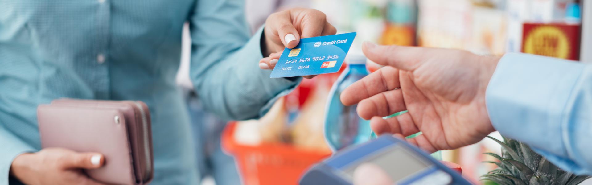 Woman at the store checkout handing card to cashier