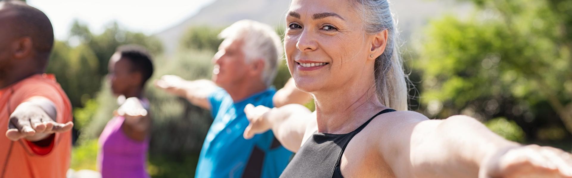 Senior woman stretching arms in yoga class