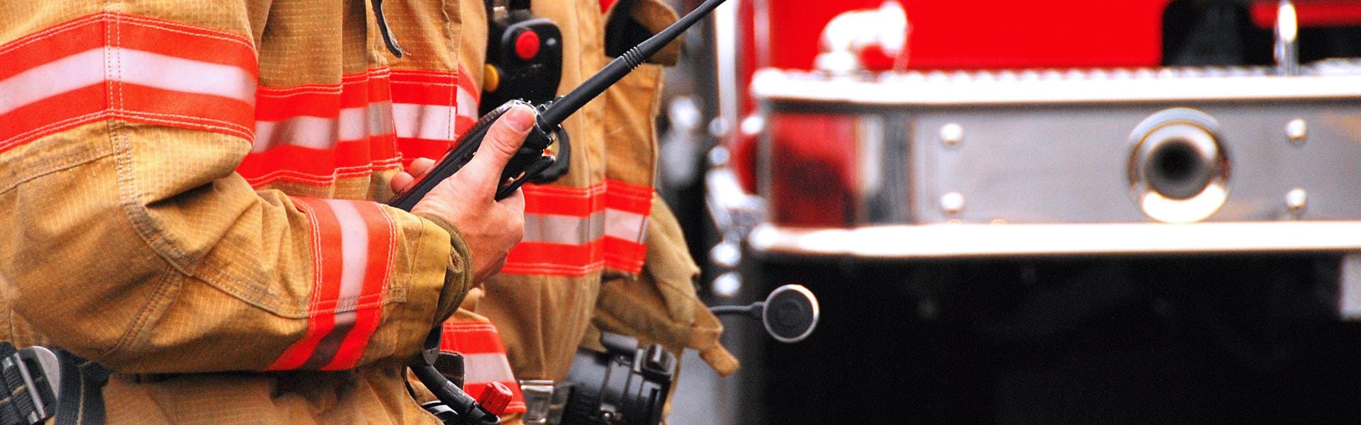 Firefighter standing with walkie talkie in front of fire truck