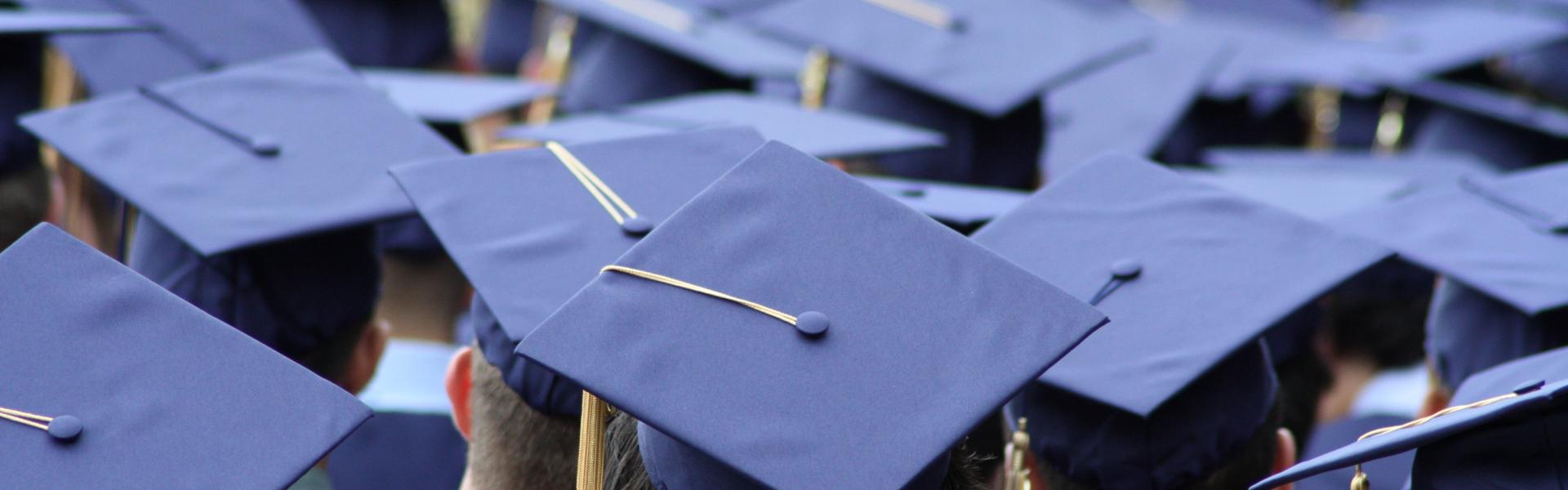 Students in graduation gowns and caps sit during their ceremony