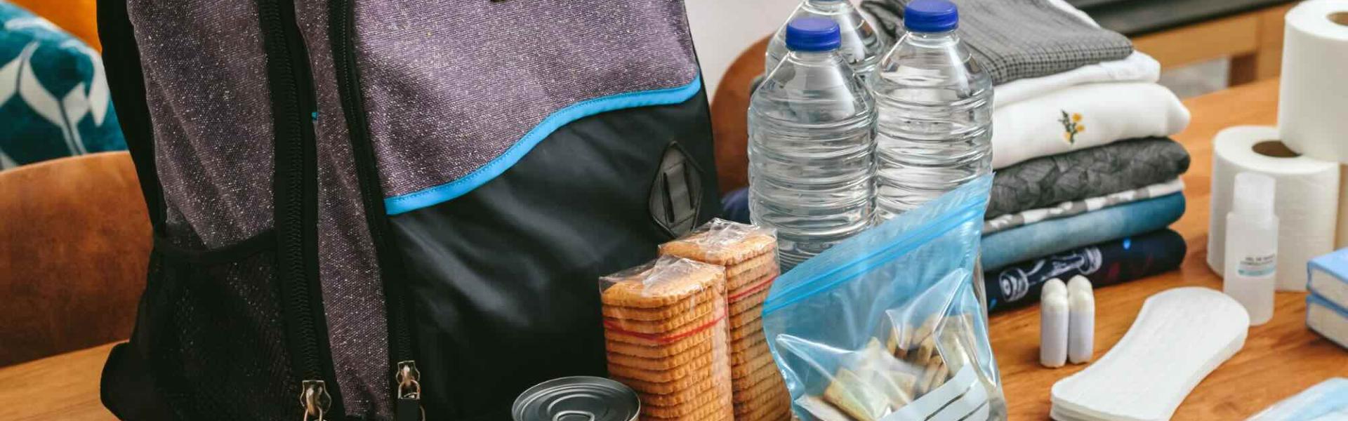 emergency kit supplies sitting on a table in front of a purple backpack