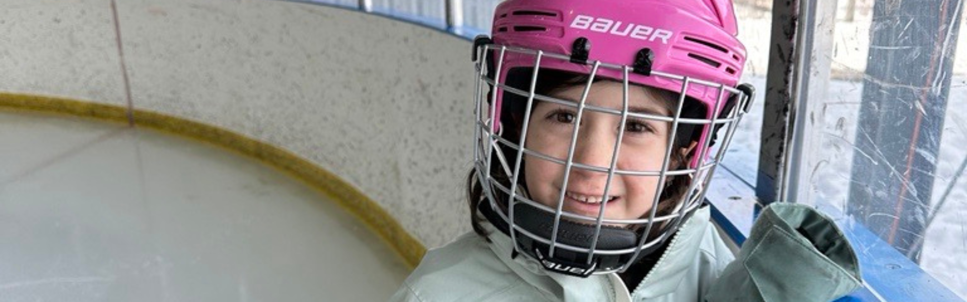 A girl wearing a pink ice skating helmet.