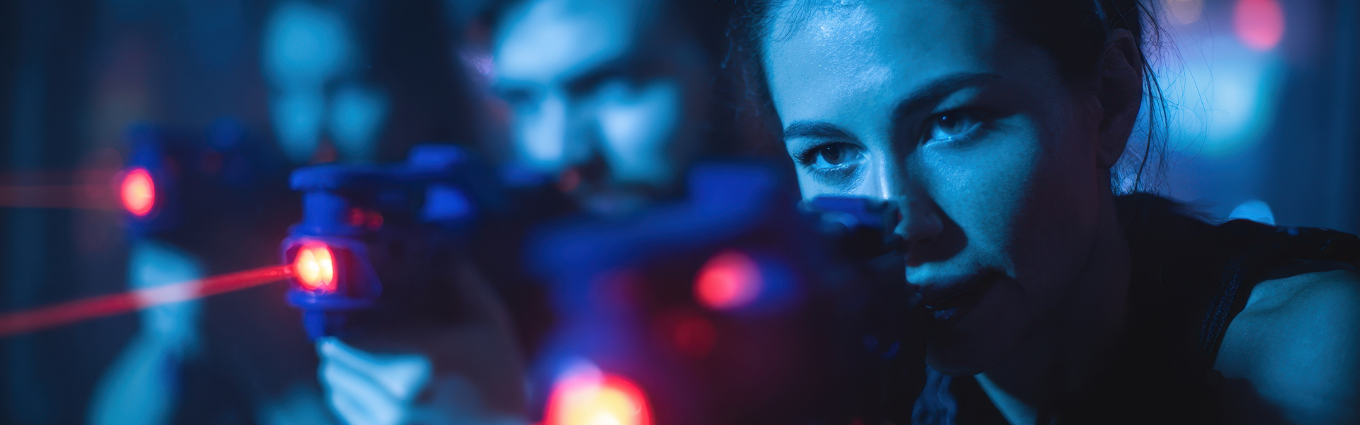 Three laser tag players standing in a line and pointing their lasers.