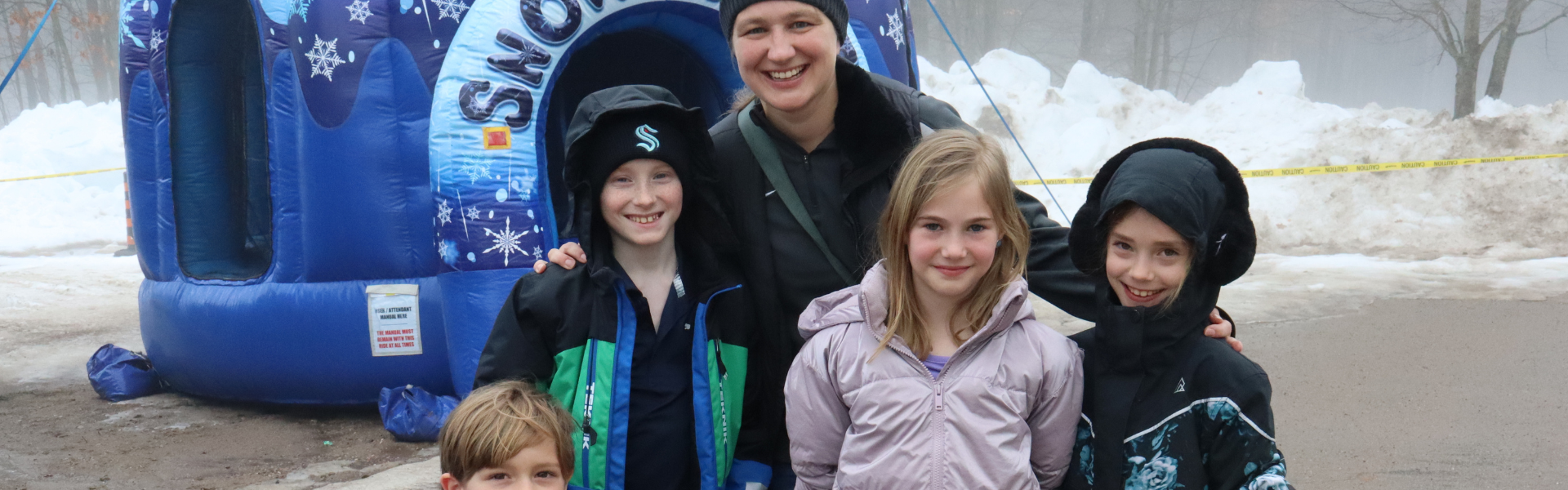 Smiling family in front of a winter themed bouncy castle