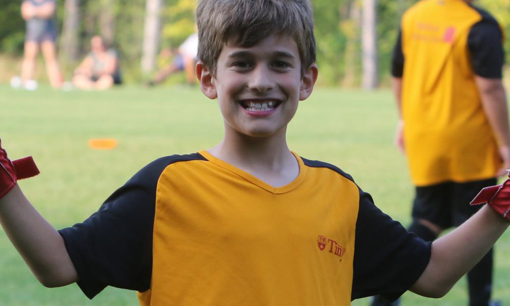 Youth soccer player smiling and waving hands