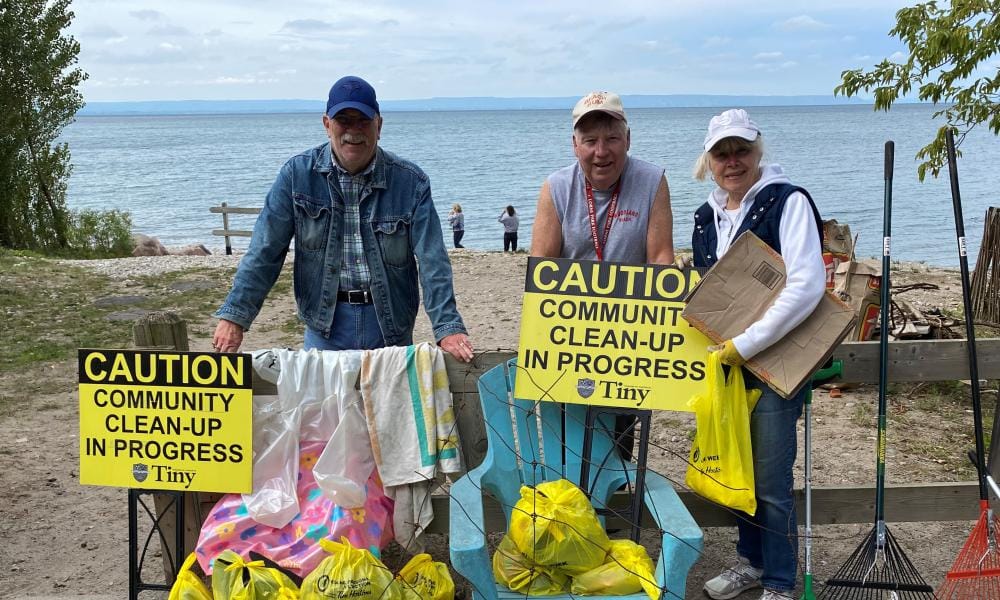 A group of volunteers poses for a picture while cleaning up litter at Cawaja Beach