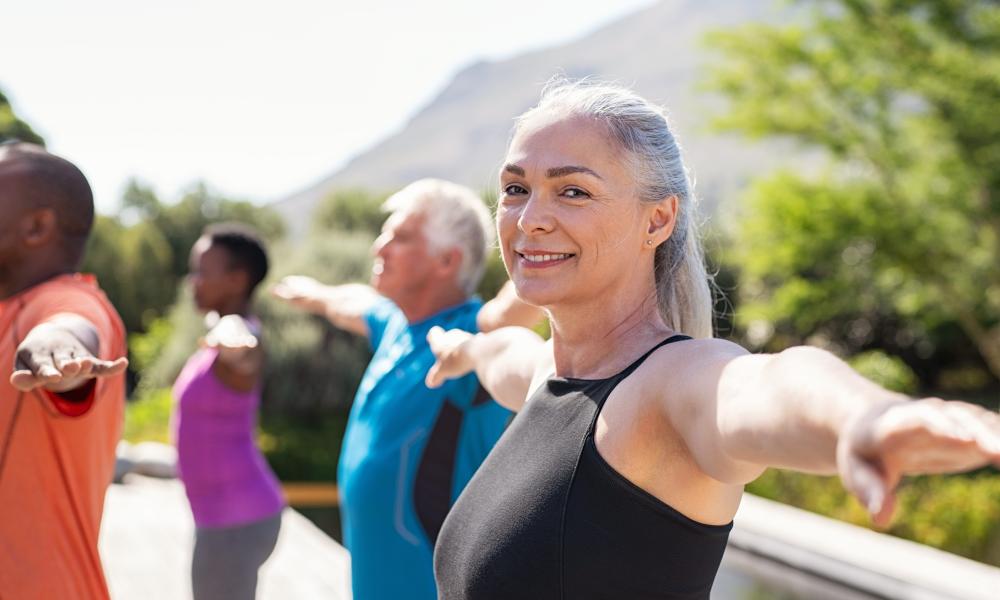 Senior woman stretching arms in yoga class
