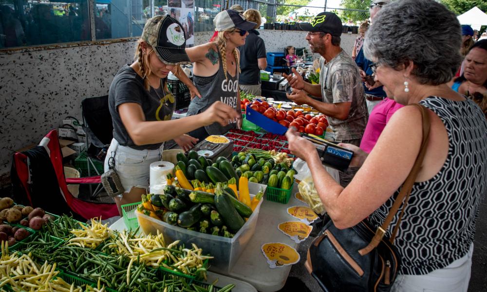 Vegetable vendor serves customer at vendor fair