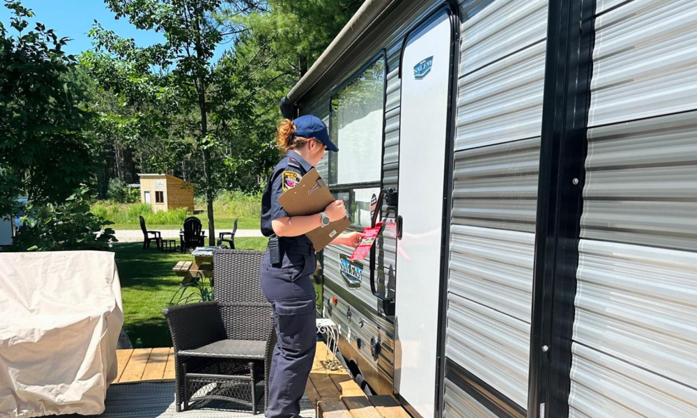 woman firefighter holding a checklist following up at a homeowner's front door