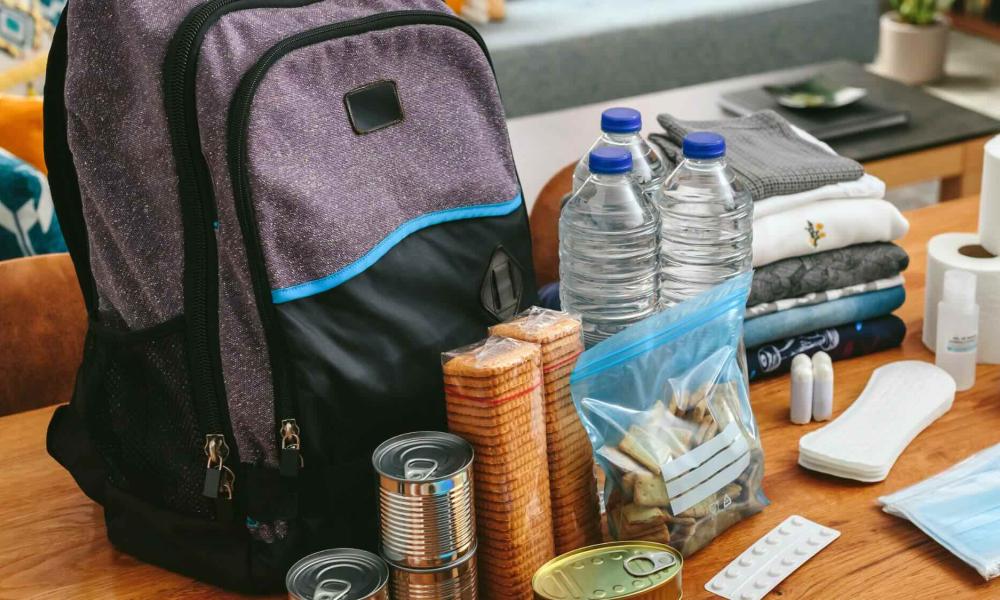 emergency kit supplies sitting on a table in front of a purple backpack