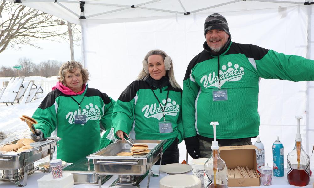 three township of tiny volunteers dressed in wyevale public school bright green jerseys at the winter carnaval d'hiver pancake station