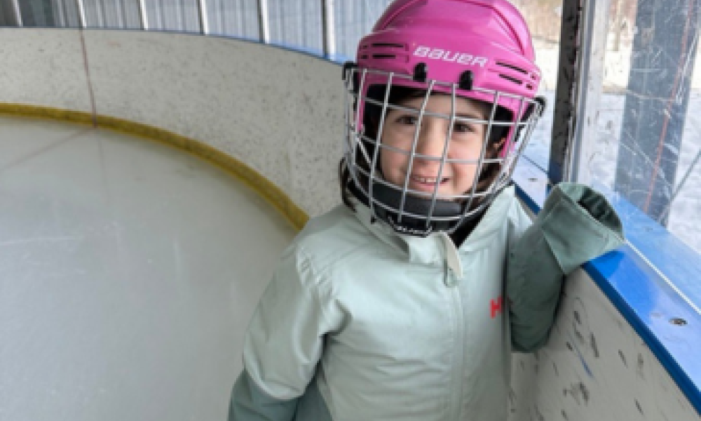 A girl wearing a pink ice skating helmet.
