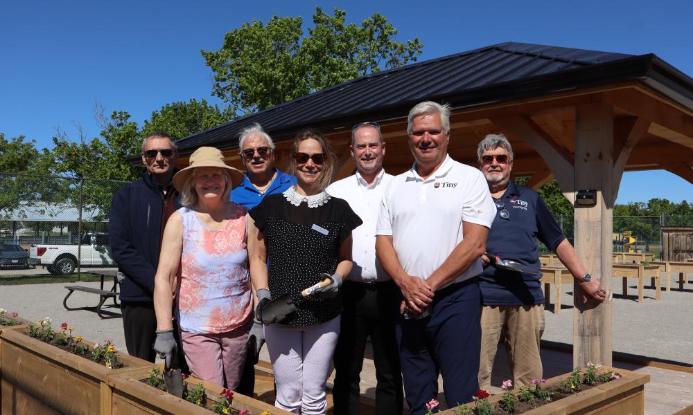 Members of Tiny Council, MPP Assistant Leslie Stroud, Accessibility Advisory Committee members posing in front of gazebo with flower box in front