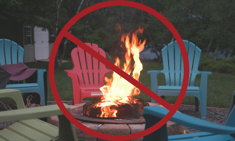 Large red prohibited sign on an image of a campfire with multiple coloured chairs