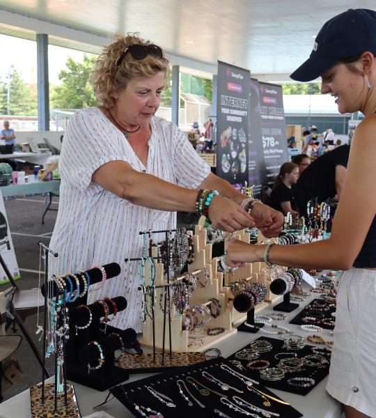 woman interacting with a local jewelry maker at their booth