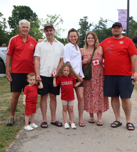 Large group of family/friends all dressed in red and white with two young children in the middle.