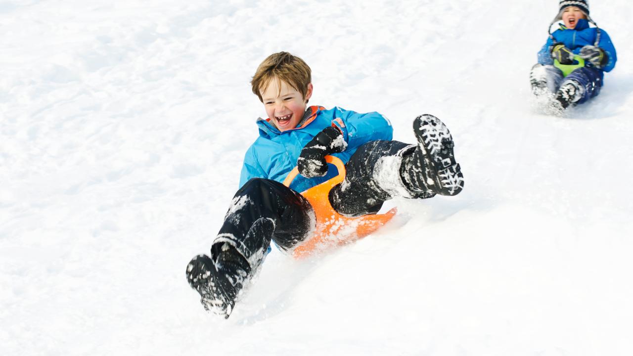 Young boys tobogganing and having fun in the snow