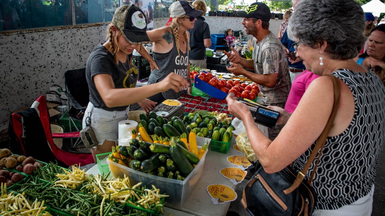 Vegetable vendor serves customer at vendor fair