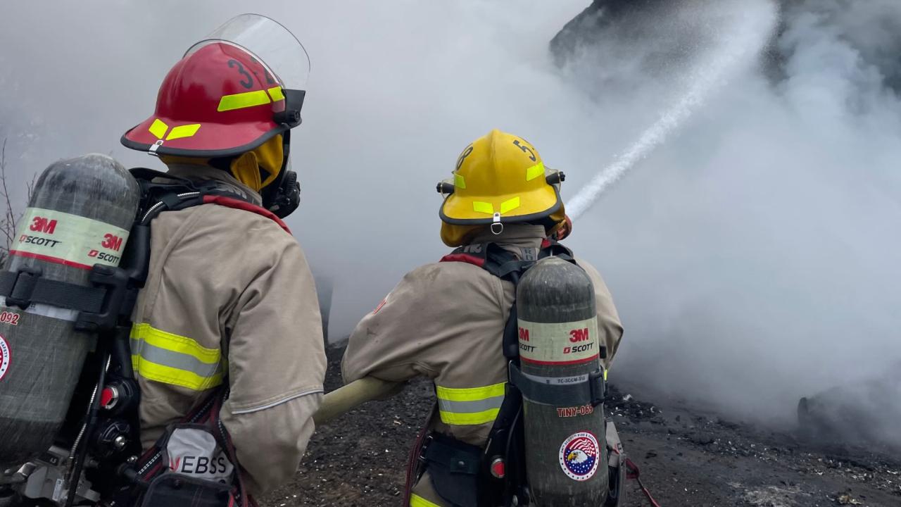 firefighters battling a fire with the house and the area is filling with thick smoke