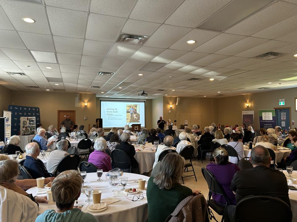 group of participants at the senior symposium sitting at tables and listening to a presentation