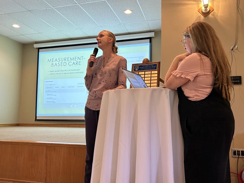 Two women standing near the front of the stage presenting at the senior sympoisum