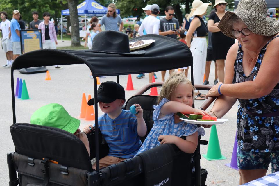 grandmother offering watermelon to granchildren in a covered wagon