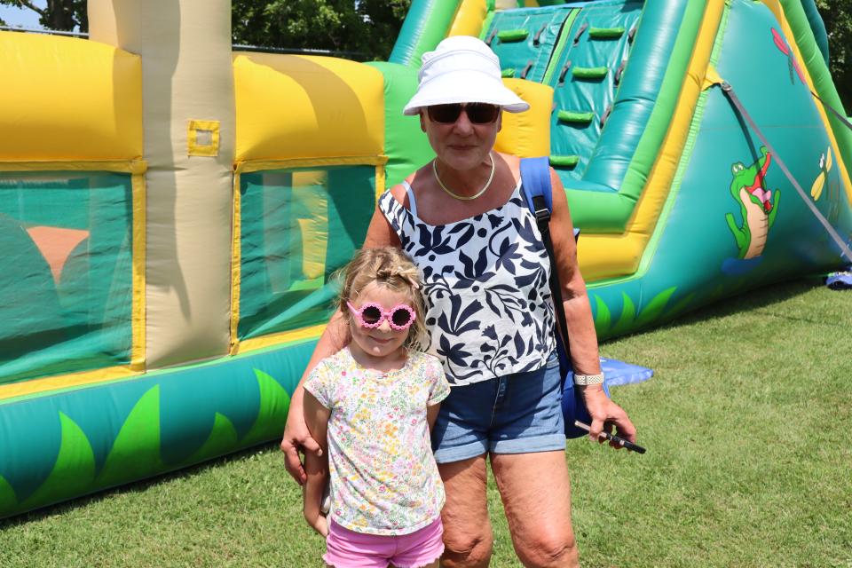 grandmother and granddaughter standing in front of a large bright green and yellow inflatable