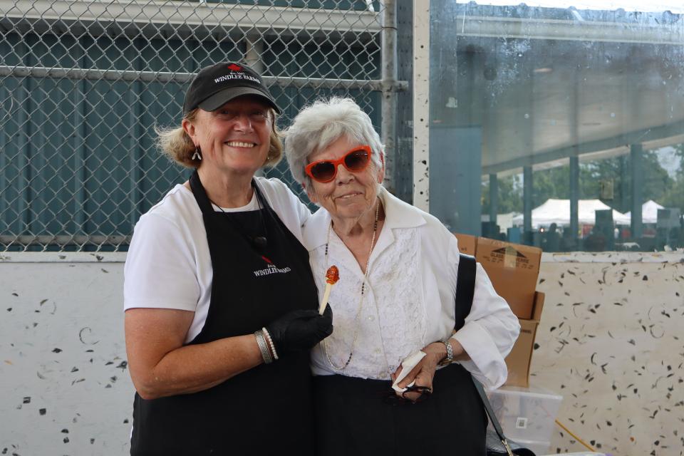 Windlee Farms staff holding their fresh maple taffy on a stick with a friend and resident
