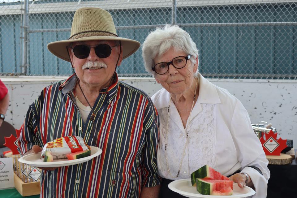 couple in the pavillion posing together with plates filled with watermelon