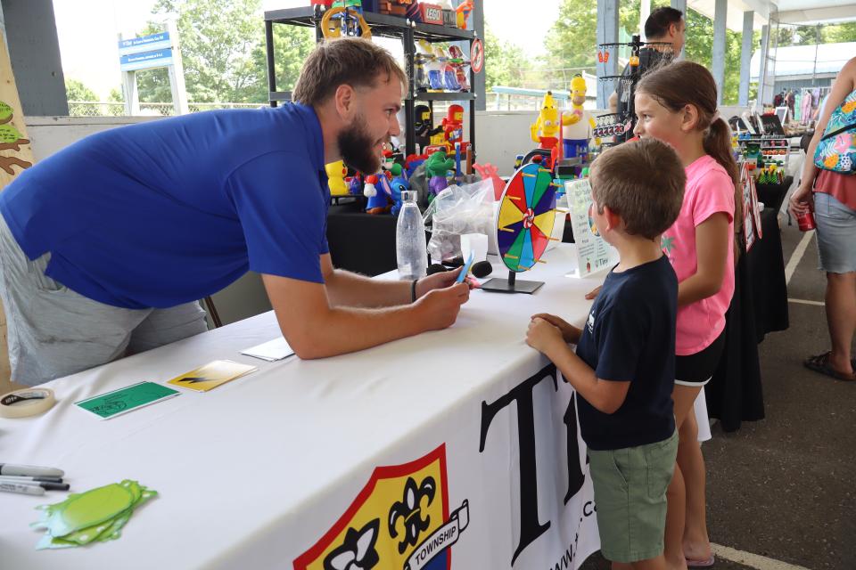 Tiny environmental staff engaging with two young siblings at their booth 