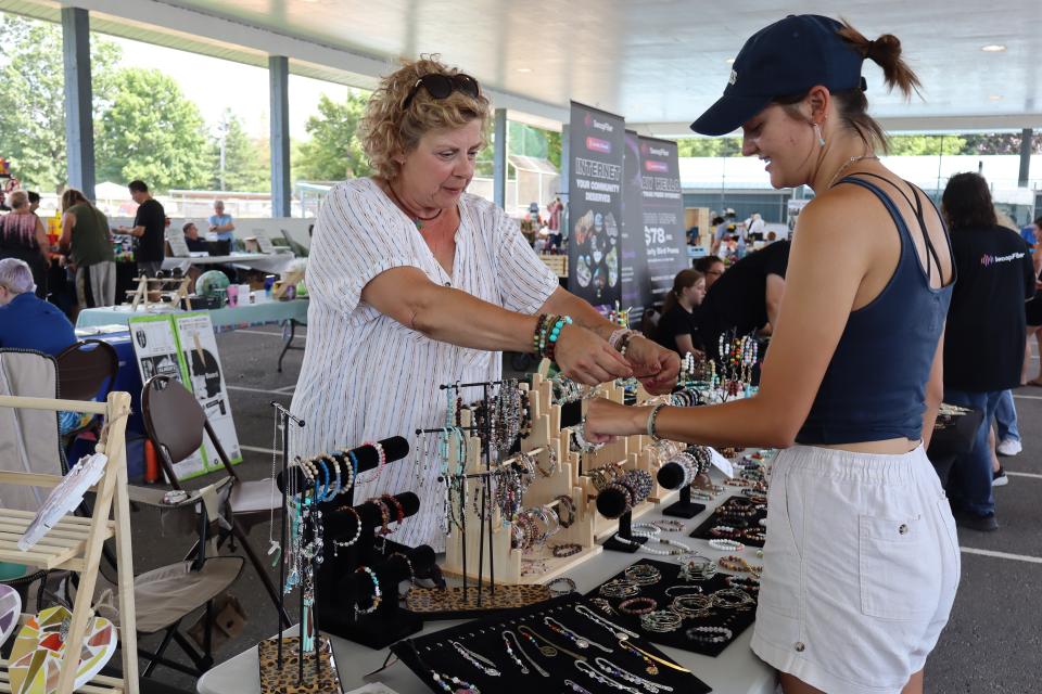 woman interacting with a local jewelry maker at their booth