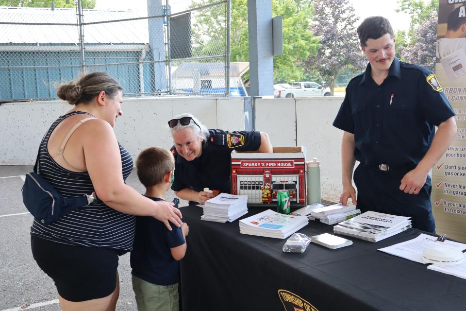 mom and son interacting with a female firefighter at the firefighter's safety booth inside the pavillion