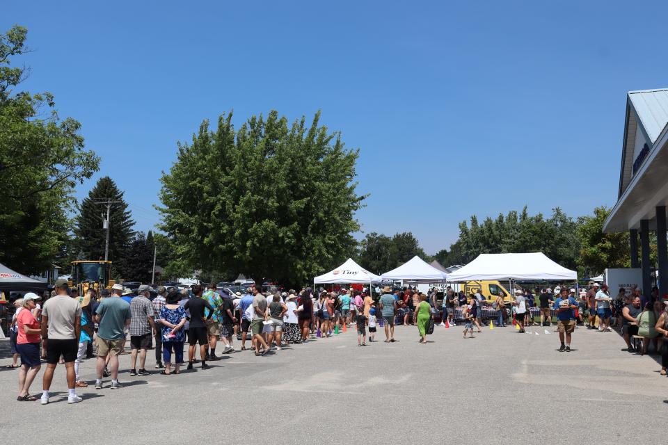 view of the crowd at the food line with several tents housing staff and volunteers working the barbecue in the back