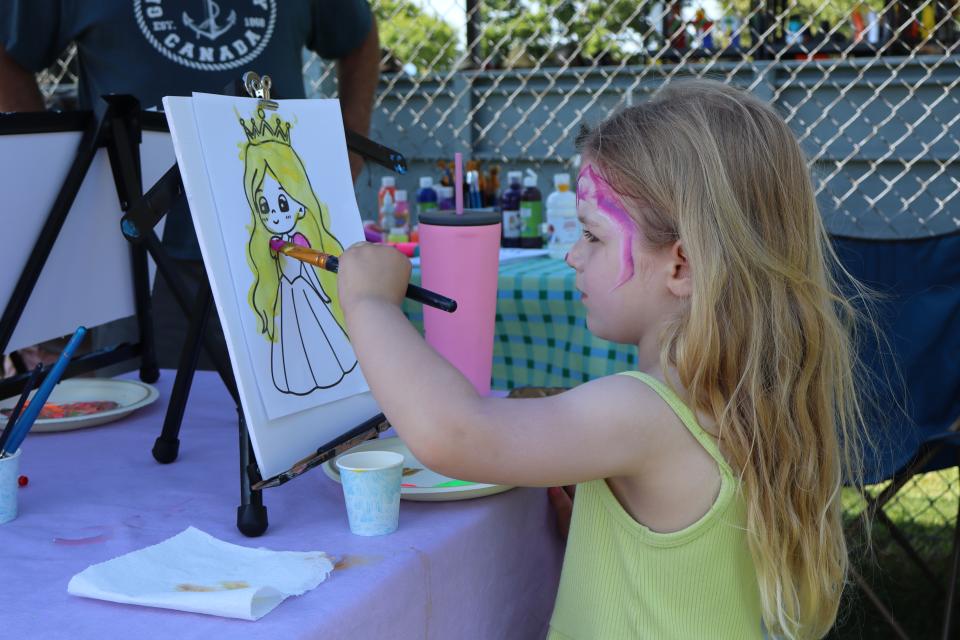 girl with colourful facepaint painting a princess picture at the Tiny Fun Art booth