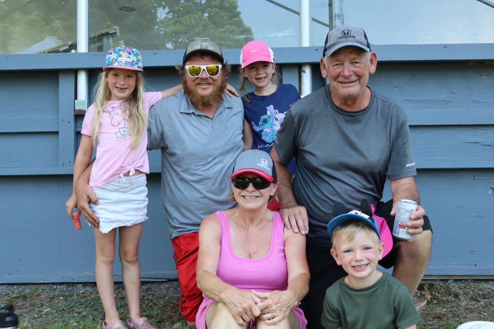 Three generations of a family posing in front of the Perkinsfield Pavillion during lunch at the community bbq