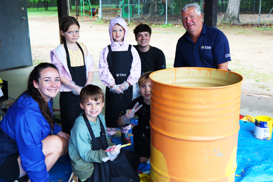 Staff, students, one of our local artists, and Mayor David Evans posing with one of the waste barrels being painted with a bee theme