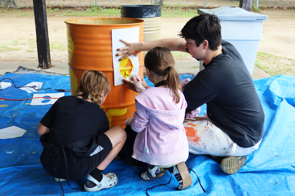 local artist holding up a hexagon stencil for students to paint
