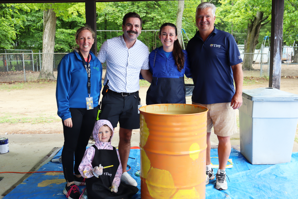 Wyevale Central Public School teacher and principal, Tiny staff, Mayor David Evans and a student posing with a bright orange and yellow painted waste barrel