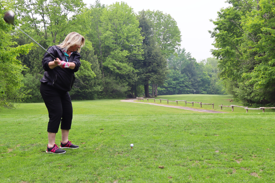 Woman mid-swing on the longest drive hole with the perspective behind the golfer.