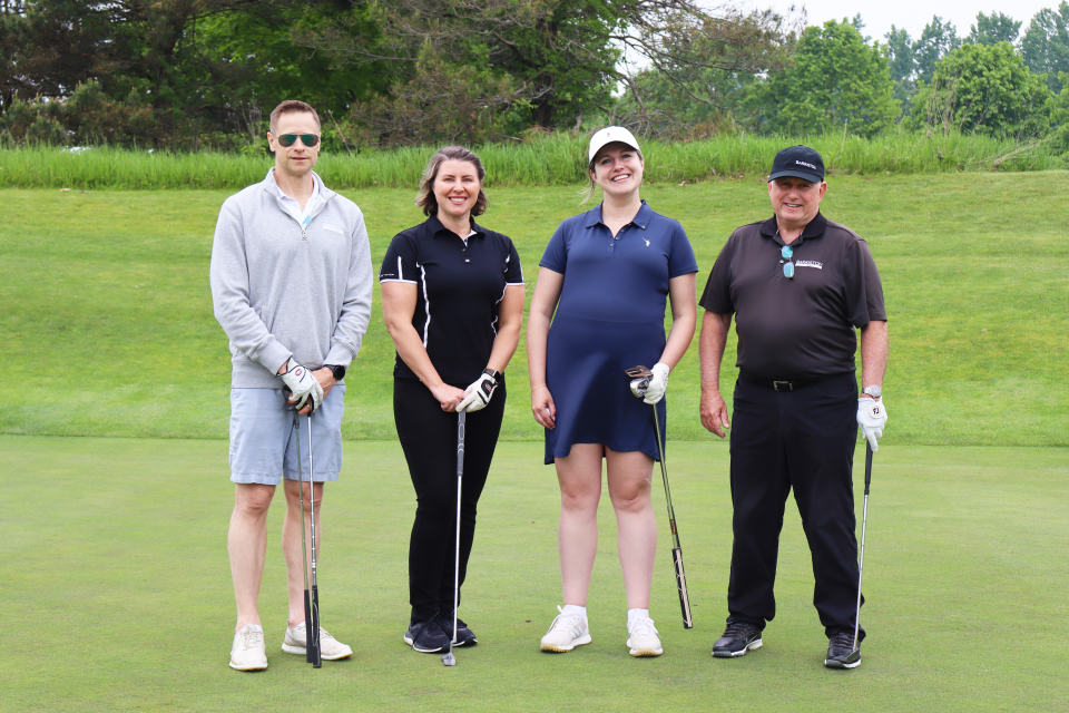 Gold foursome posing together with big smiles. 