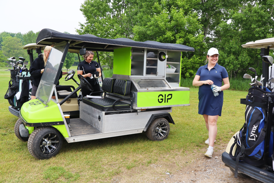 Golf participants purchasing from while others walk away from the snack cart with purchased water.