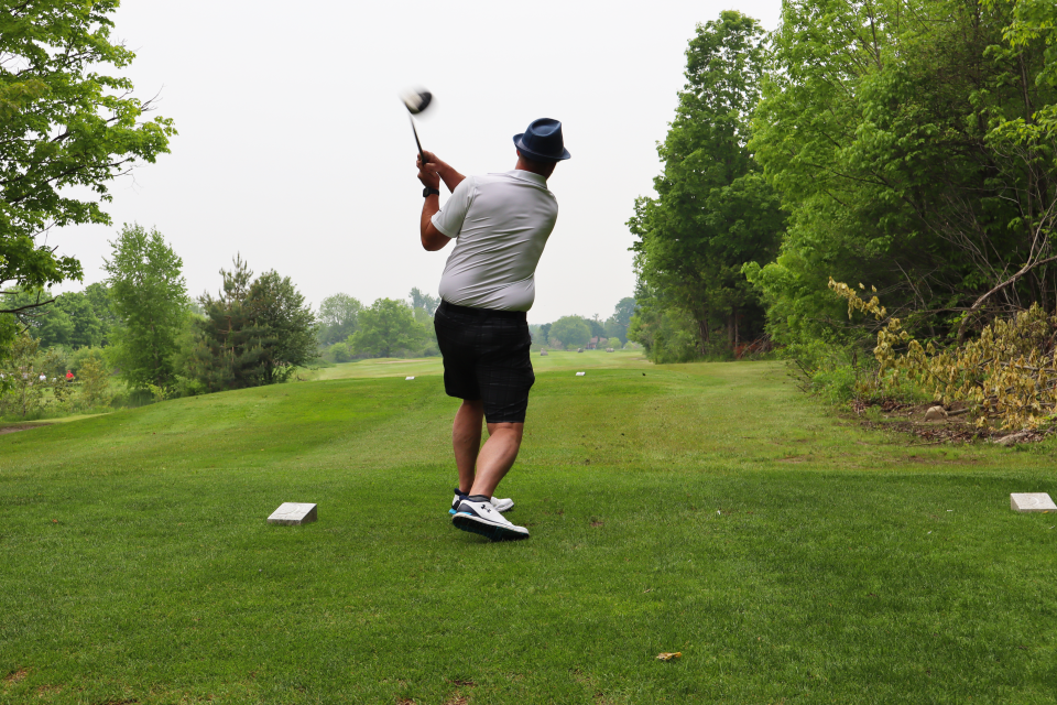 Deputy Mayor Miskimins in the middle of a swing with the view from behind looking down the course.