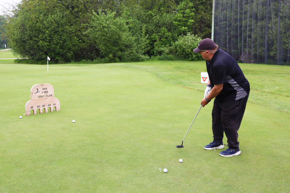Man participating in the mini-putting challenge course game, with their ball headed toward the target.