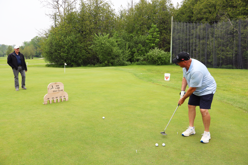 Man participating in the mini-putt challenge with someone looking on in the background.