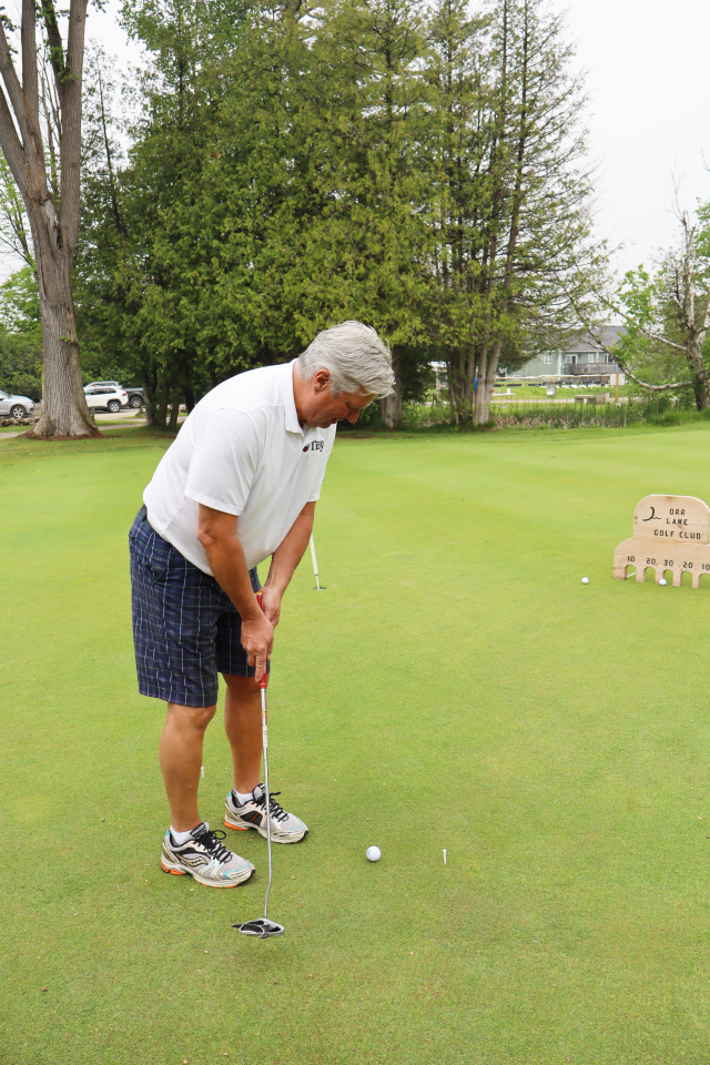 Mayor David Evans lining up a golf swing at the putting contest.