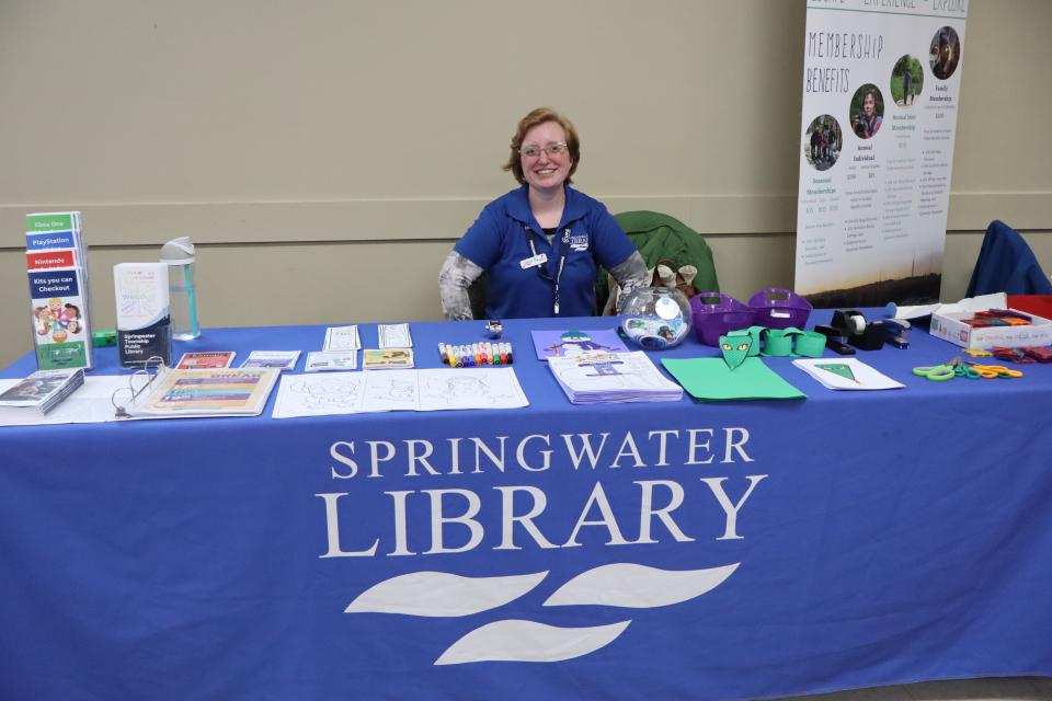 Springwater public library staff member at their booth with many crafts on the table available for kids