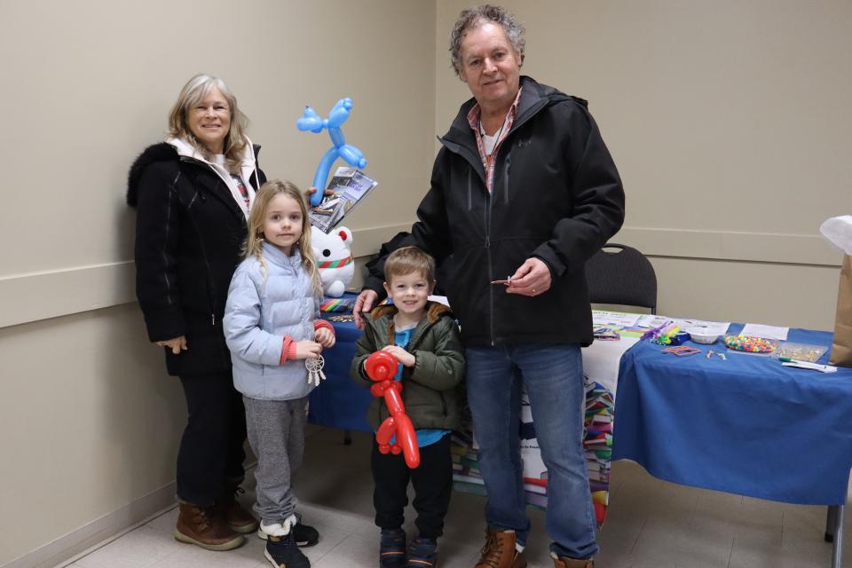 Family with two young children holding balloon animals at the Penetanguishene Public Library booth