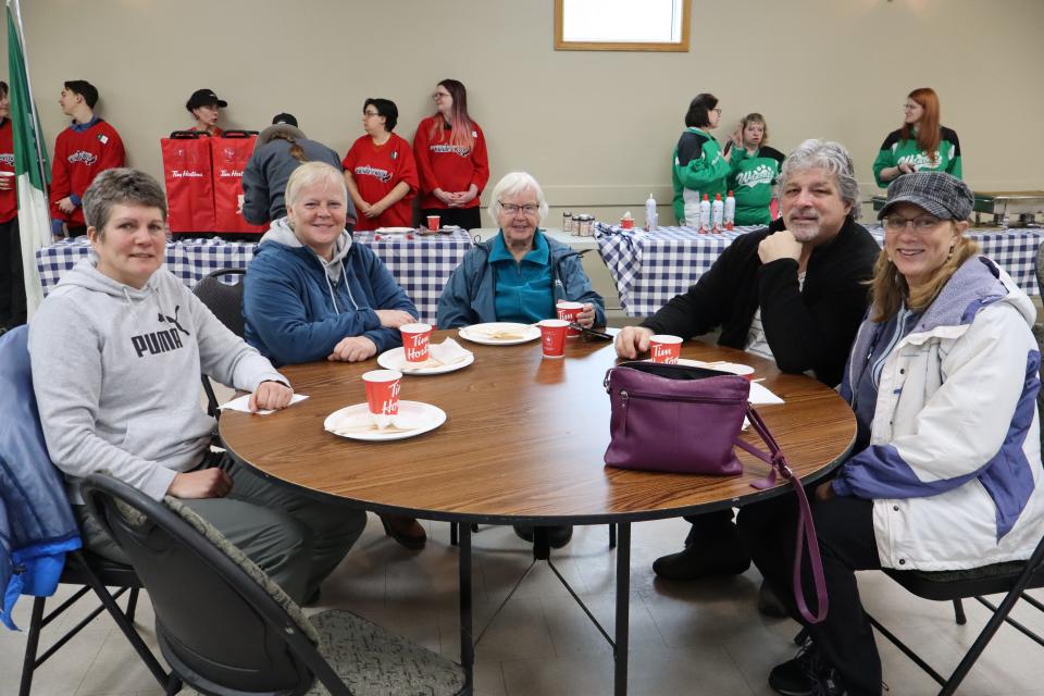Group of adults chatting after lunch around a circular table inside the community centre