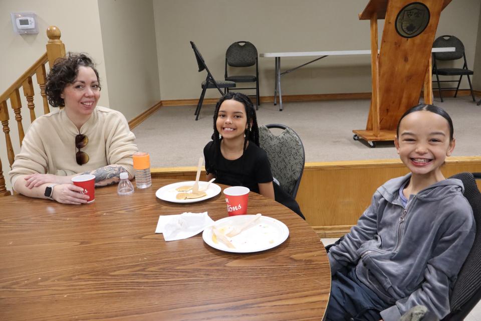 Young family enjoying pancakes and hot chocolate at a round table