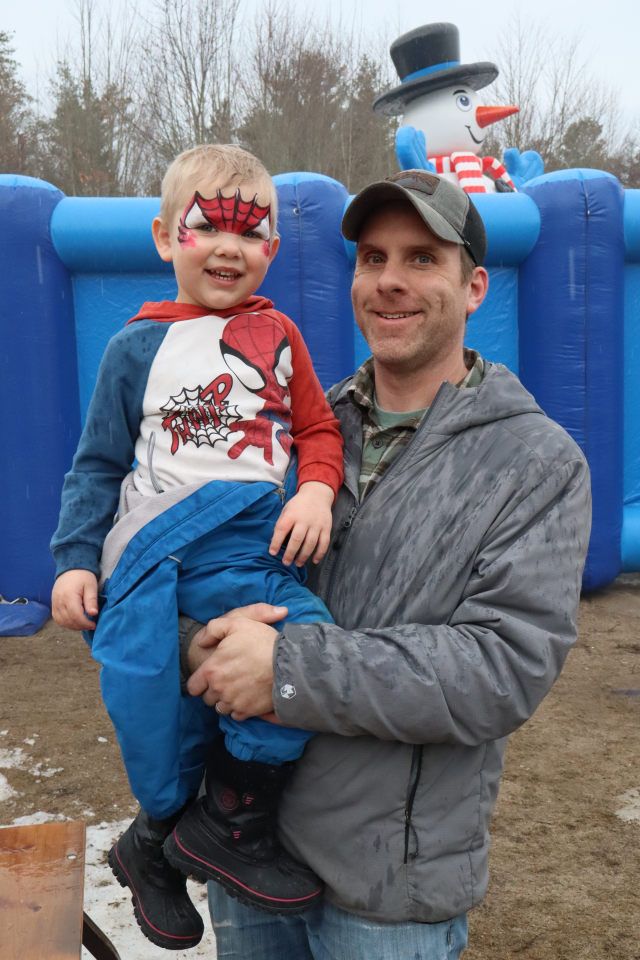 Dad carrying young son with face paint made to look like spider man